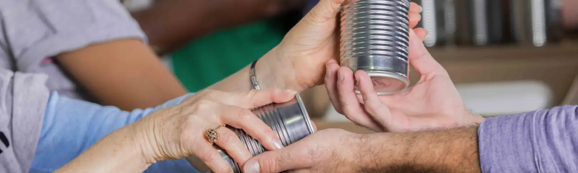 people handing canned food to each other