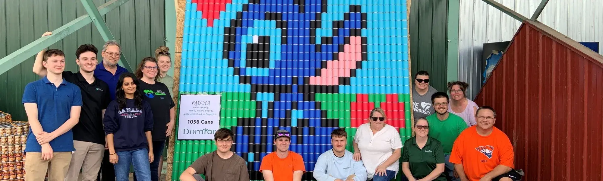 Team posing in front of their sculpture made of cans