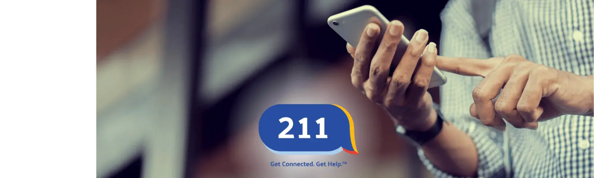 Photo of a man holding a smartphone and the 211 logo.